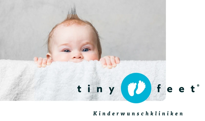 Baby schaut ueber eine Decke, Tiny Feet Kinderwunschkliniken Logo mit zwei kleinen Fueßen auf blauem Hintergrund, Fruchtbarkeitsbehandlung und Kinderwunschzentrum