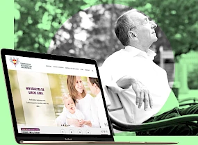 Website der Oesterreichischen Gesellschaft vom Goldenen Kreuz auf einem Laptop. Im Hintergrund ein aelterer Mann entspannt auf einer Parkbank