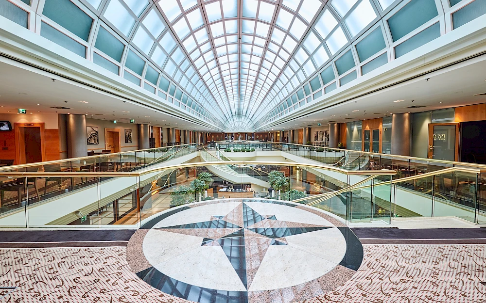 Modernes, lichtdurchflutetes Atrium eines Hotels in Wien mit glaeserner Kuppeldecke, im Vordergrund kunstvolles Mosaik im Bodenbelag