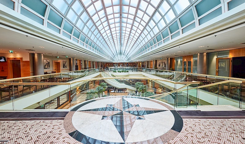 Modernes, lichtdurchflutetes Atrium eines Hotels in Wien mit glaeserner Kuppeldecke, im Vordergrund kunstvolles Mosaik im Bodenbelag