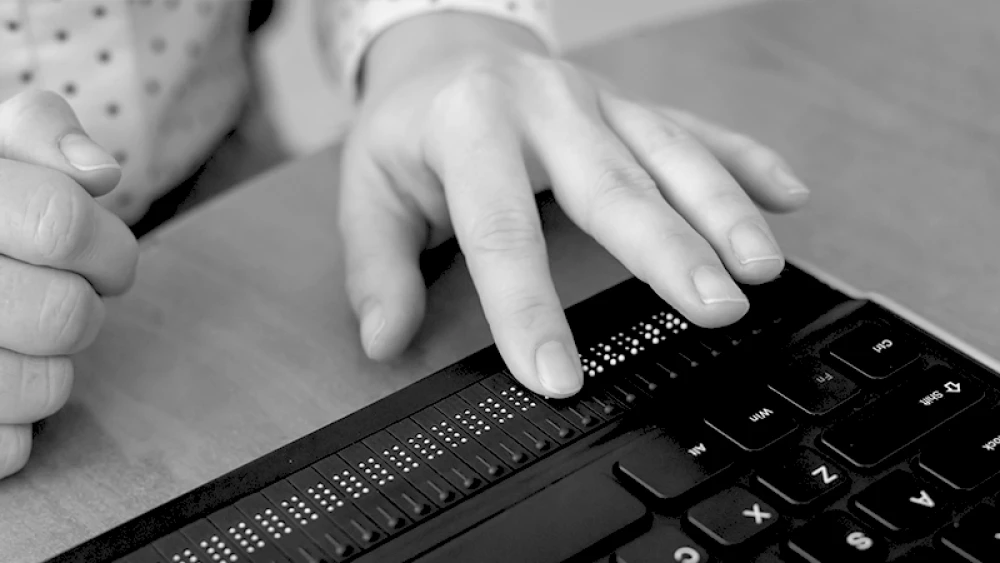 Hand benutzt Blindenschrift auf Computertastatur