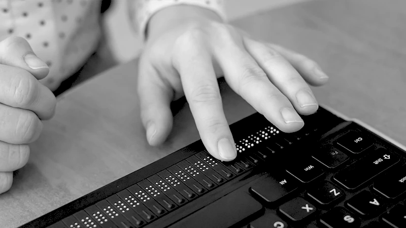 Hand benutzt Blindenschrift auf Computertastatur