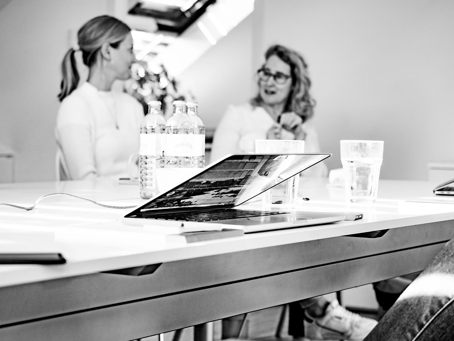 Laptop und Wasserflaschen auf Tisch bei Meeting