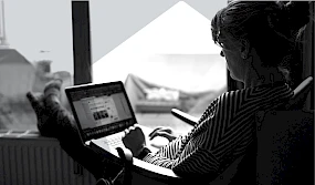 Frau lehnt gemuetlich in Sessel mit Laptop