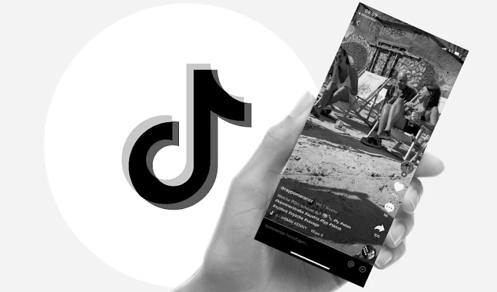 Hand haelt Smartphone das Video abspielt, daneben TikTok Logo