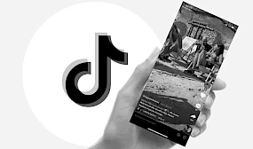 Hand haelt Smartphone das Video abspielt, daneben TikTok Logo