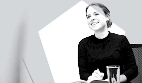 Junge lachende Frau schreibt mit Stift in Notizbuch