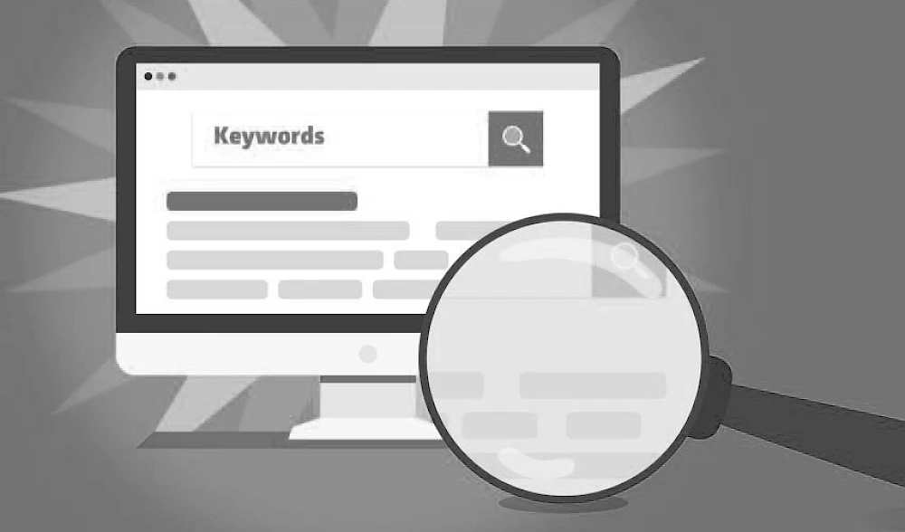 Computerbildschirm zeigt das Wort Keywords in einer Suchmaschine, waehrend eine Lupe die Bedeutung der Keyword-Analyse hervorhebt