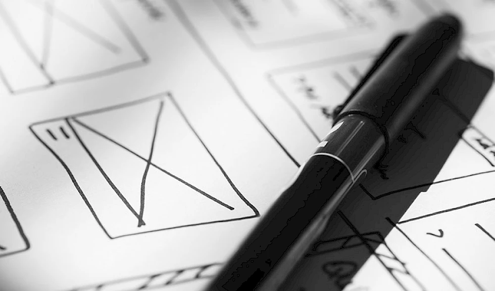Skizze eines Webdesign-Layouts und einem Stift auf Papier