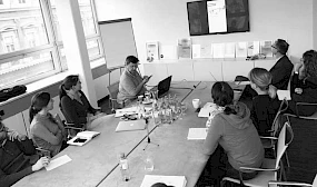 Besprechung in einem modernen Konferenzraum, in dem ein Team eine Praesentation auf einem Bildschirm verfolgt