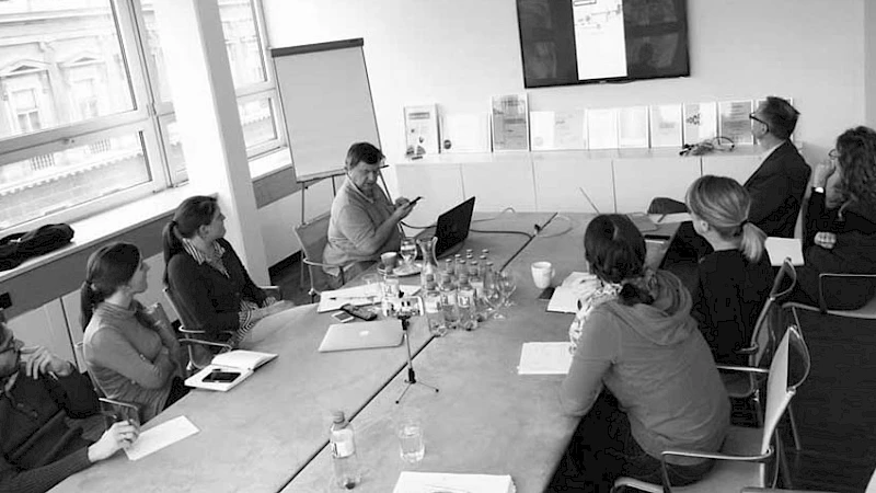 Besprechung in einem modernen Konferenzraum, in dem ein Team eine Praesentation auf einem Bildschirm verfolgt