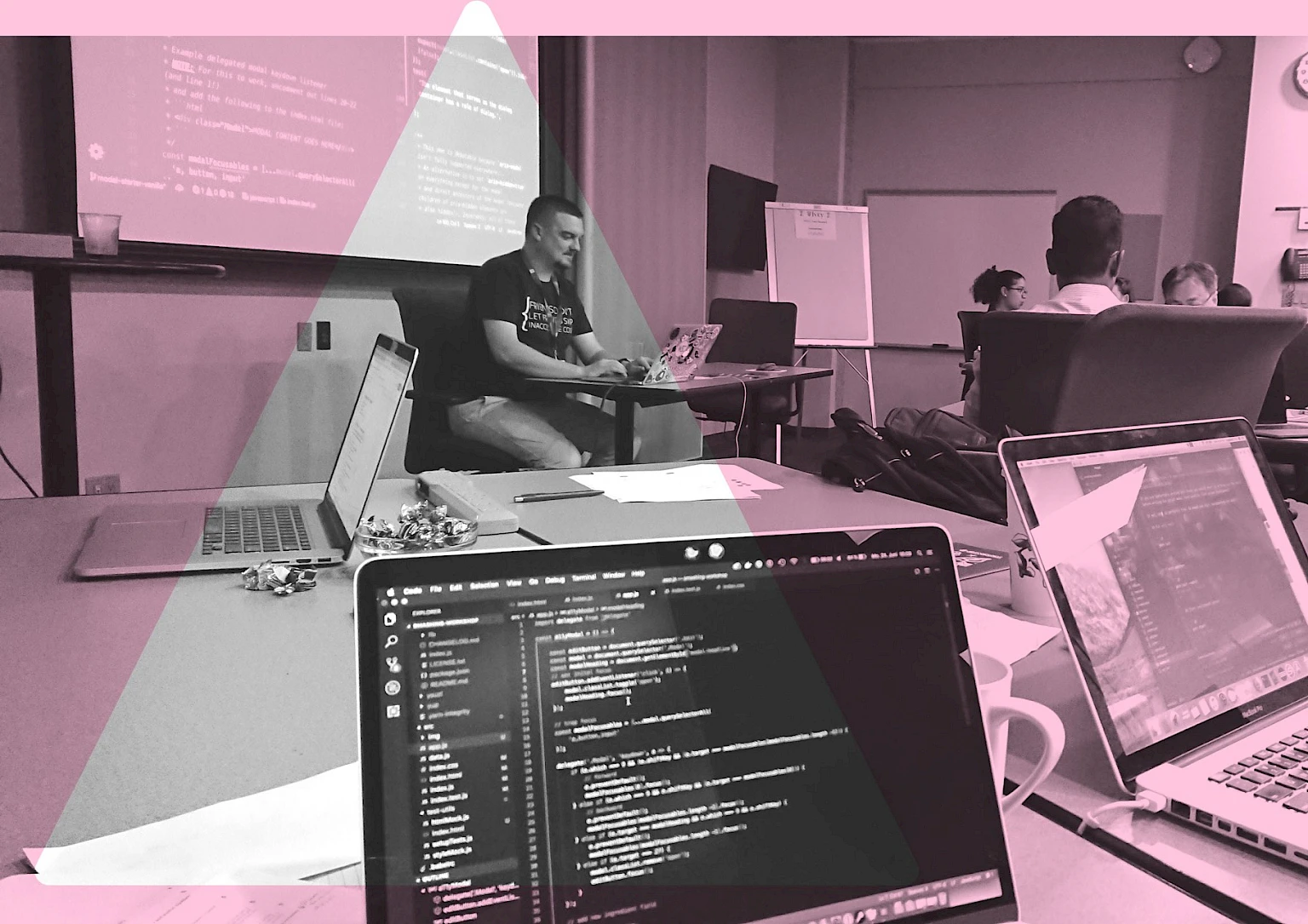 Workshop mit Entwicklern in Seminarraum, mehrere geoeffnete Laptops mit Code-Editoren